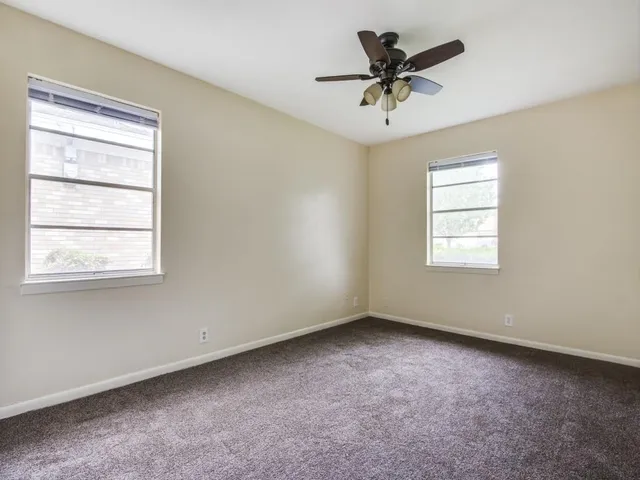 an empty room with a window and a ceiling fan