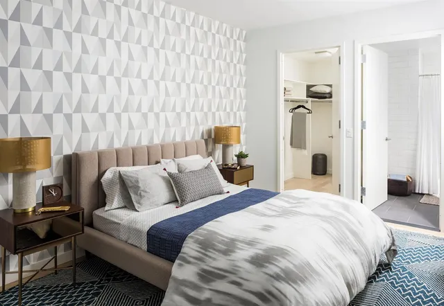 a bedroom with a bed and a lamp with the dresser