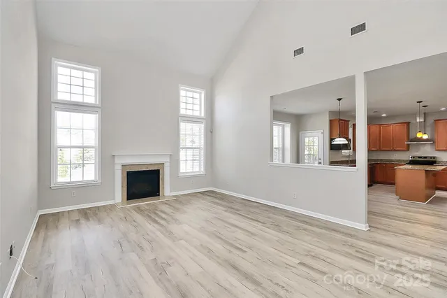 a view of empty room with wooden floor and a kitchen