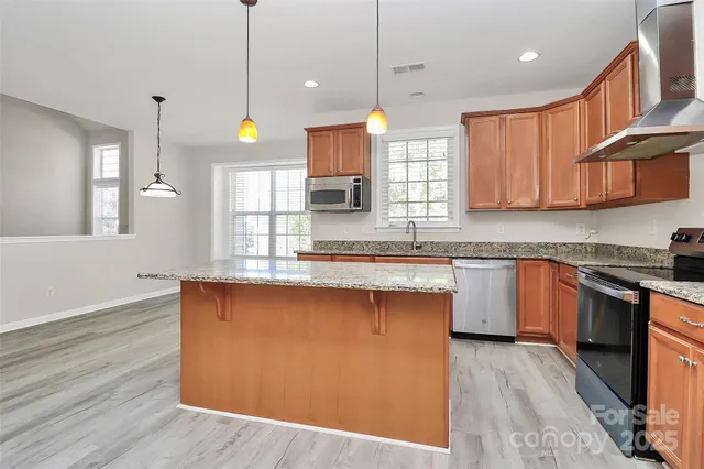 a large kitchen with granite countertop a stove a sink a center island and wooden floor