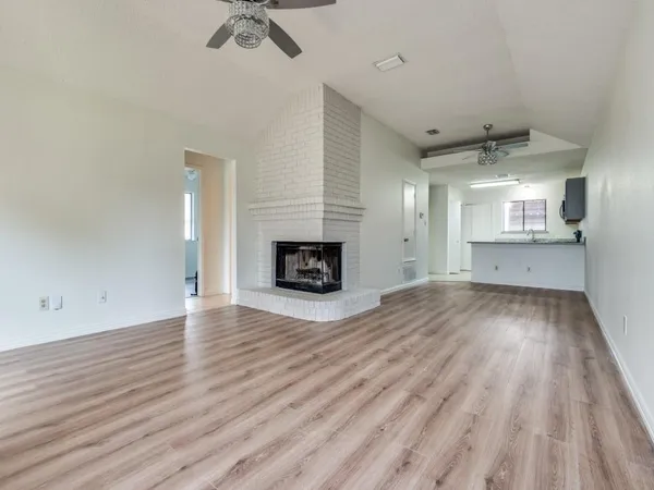 an empty room with wooden floor a fireplace and windows