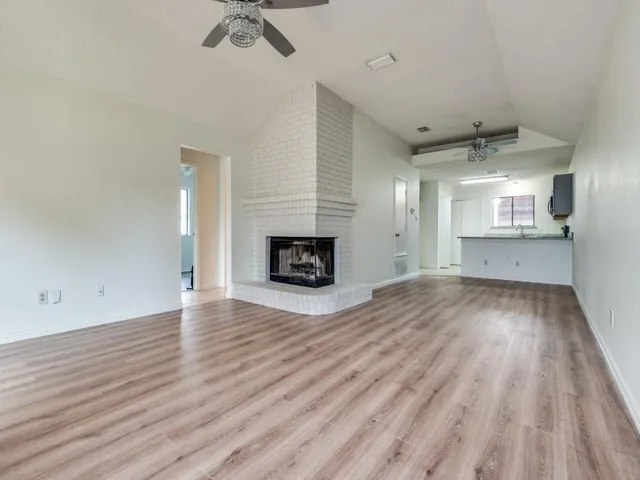 an empty room with wooden floor a fireplace and windows