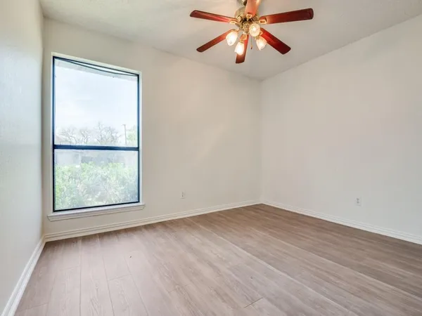 an empty room with a window and a fan