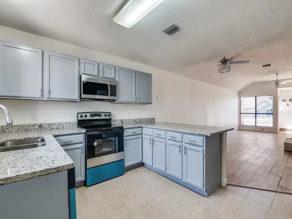 a kitchen with stainless steel appliances granite countertop a stove a sink and a microwave