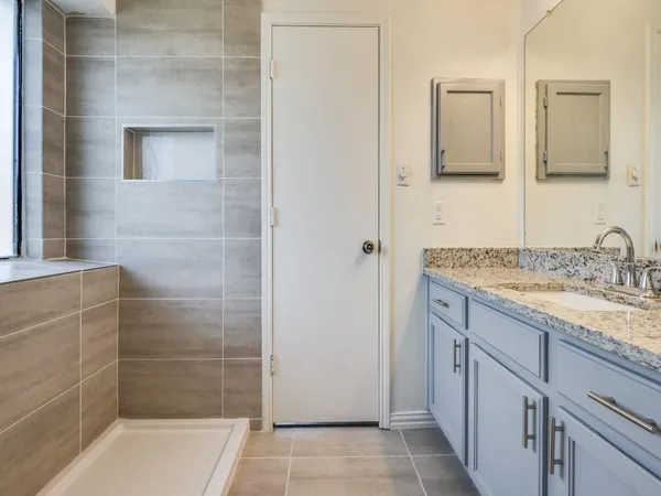 a bathroom with a granite countertop sink a shower and a mirror