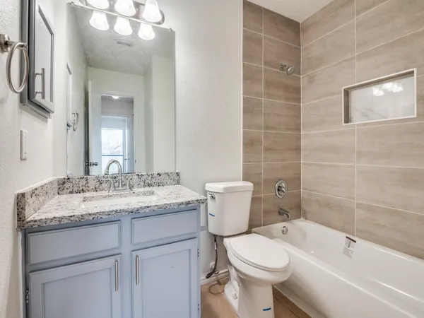 a bathroom with a granite countertop toilet a sink and a bathtub