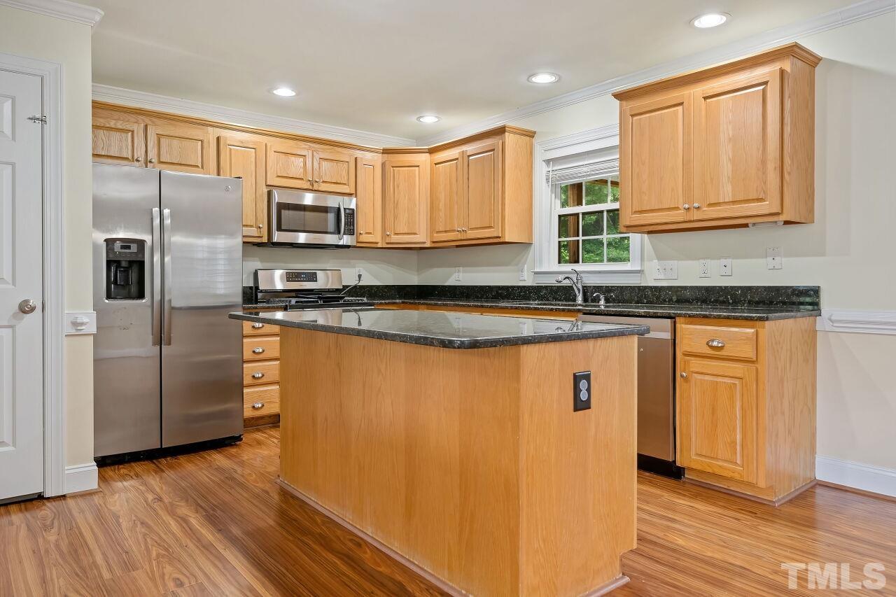 48 Eagle Pointe Lane Clayton, NC 27520 - Photo 6 of 21 a kitchen with stainless steel appliances granite countertop a refrigerator a sink dishwasher and wooden cabinets with wooden floor