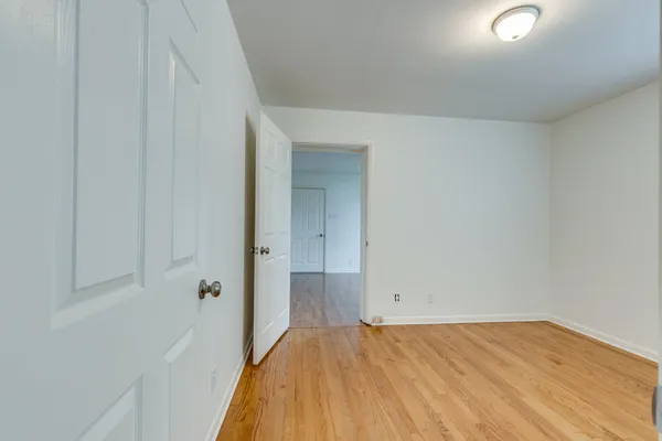 an empty room with a window and a chandelier fan