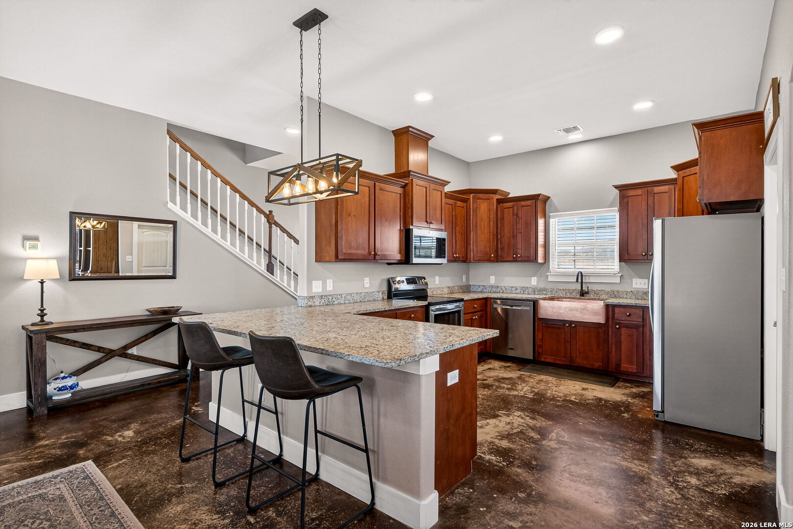 932 County Road 761 Devine, TX 78016 - Photo 17 of 47 a kitchen with stainless steel appliances kitchen island granite countertop a table chairs and a refrigerator