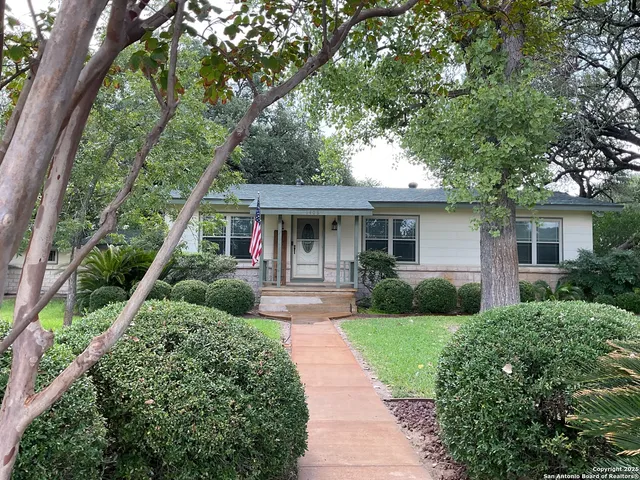 a front view of a house with a yard and potted plants