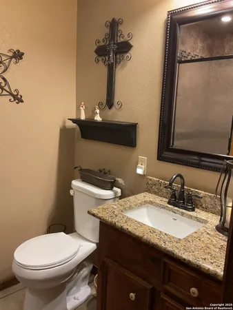 a bathroom with a granite countertop toilet sink and mirror