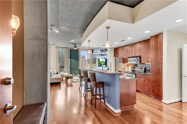 a kitchen with stainless steel appliances kitchen island granite countertop a refrigerator a stove top oven a sink dishwasher and white cabinets with wooden floor