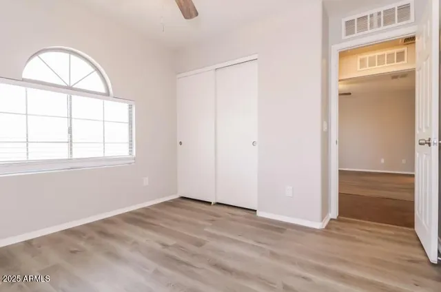 an empty room with wooden floor cabinet and windows