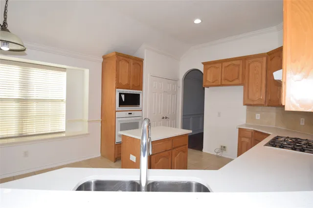 a kitchen with stainless steel appliances kitchen island granite countertop a sink and a white cabinets