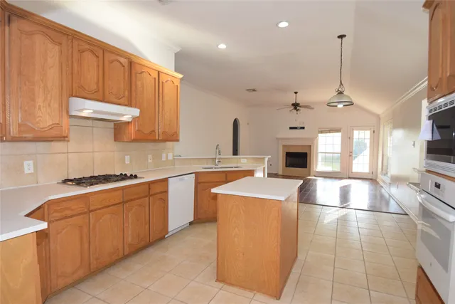a large kitchen with stainless steel appliances granite countertop a stove a sink dishwasher and a microwave oven with white cabinets