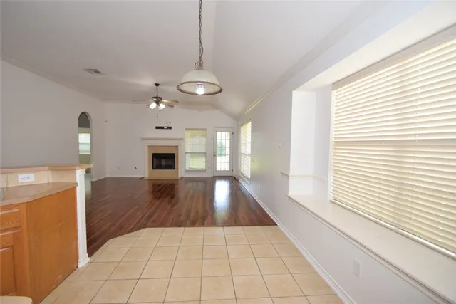 a view of an empty room with wooden floor fireplace and a window