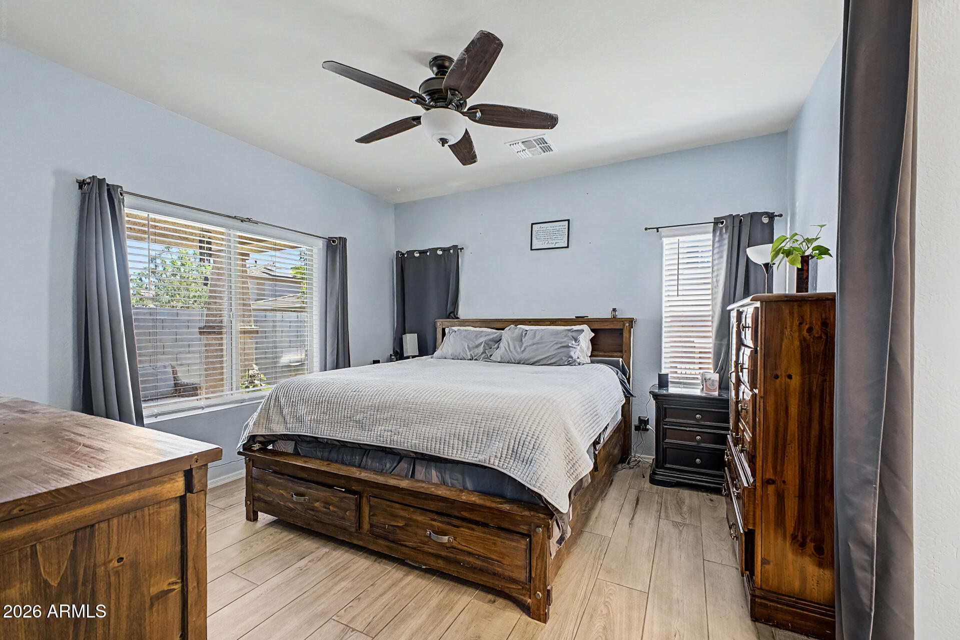 16719 West Rowel Road Surprise, AZ 85387 - Photo 11 of 28 a bedroom with a bed a dresser and a large window