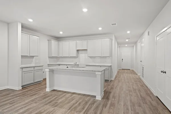 a kitchen with white cabinets appliances and wooden floor