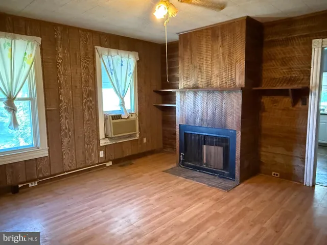 an empty room with wooden floor fireplace and windows
