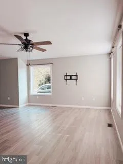 an empty room with windows and fan