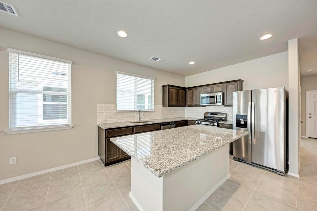 1209 Goforth Road Kyle, TX 78640 - Photo 7 of 32 A well-appointed kitchen features a large granite island and stainless steel appliances.