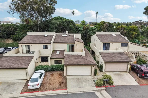 an aerial view of residential houses with city street and trees