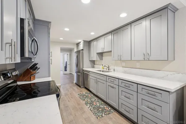 a kitchen that has a lot of cabinets in it and wooden floors