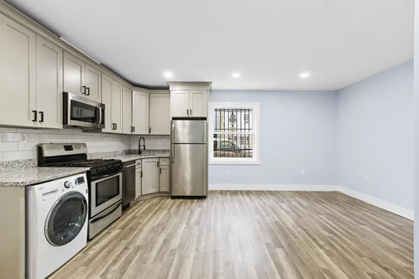 a kitchen with stainless steel appliances a stove a refrigerator cabinets and a wooden floor