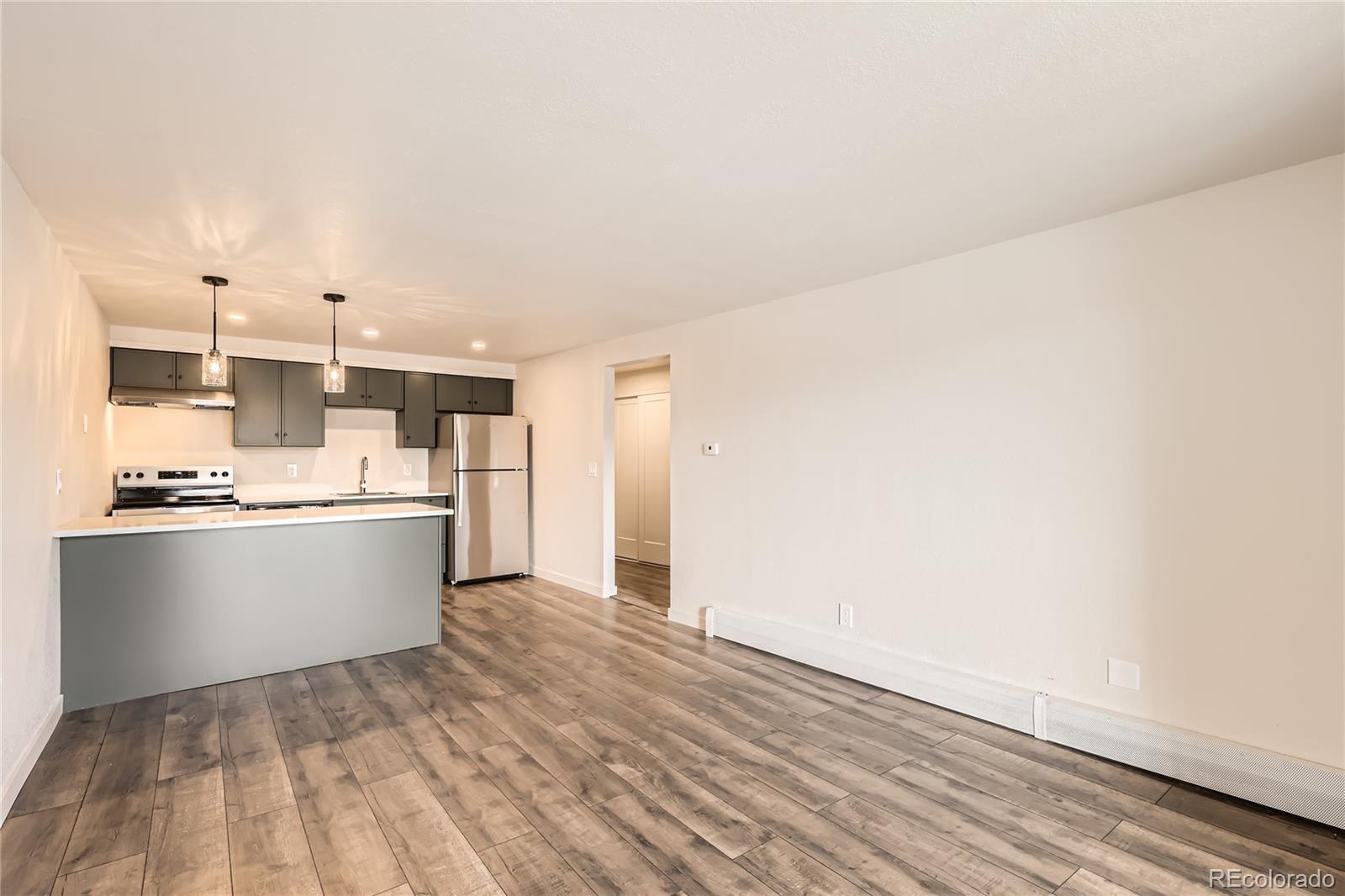 1302 South Parker Road, Unit 229 Denver, CO 80231 - Photo 5 of 18 a large kitchen with a sink and dishwasher a stove top oven with wooden floor