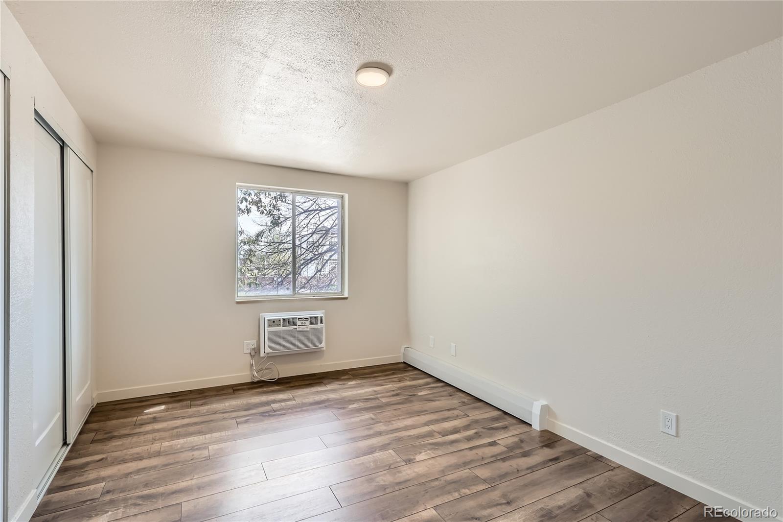 1302 South Parker Road, Unit 229 Denver, CO 80231 - Photo 8 of 18 an empty room with wooden floor and windows