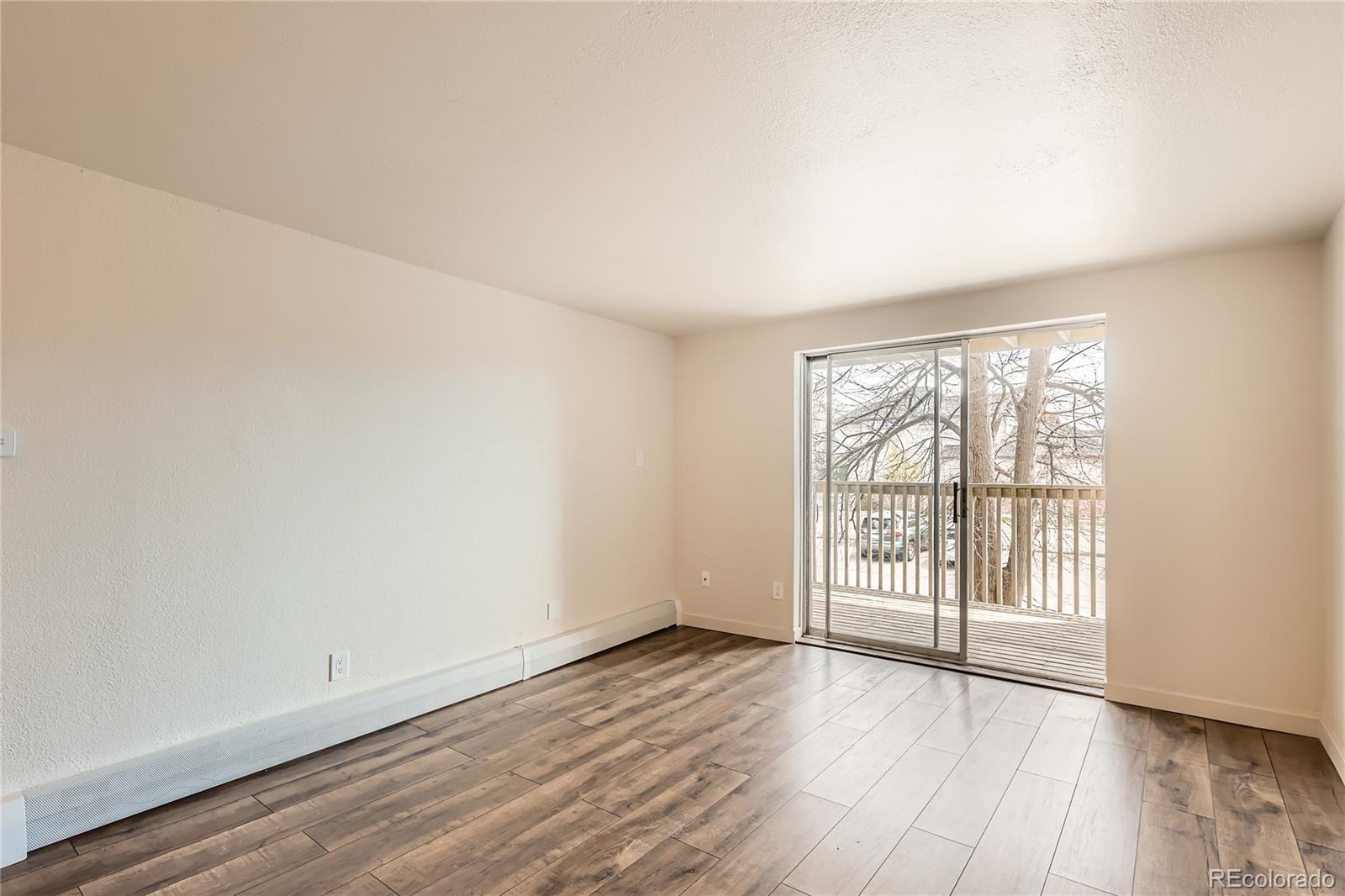 1302 South Parker Road, Unit 229 Denver, CO 80231 - Photo 10 of 18 an empty room with wooden floor and windows