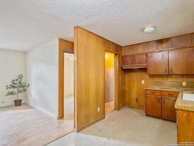 a view of a kitchen with kitchen island a sink wooden floor and a refrigerator