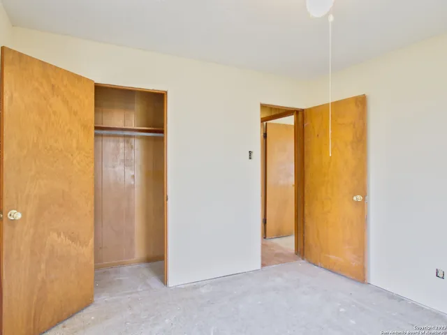 a view of an empty room with wooden floor and a bathroom