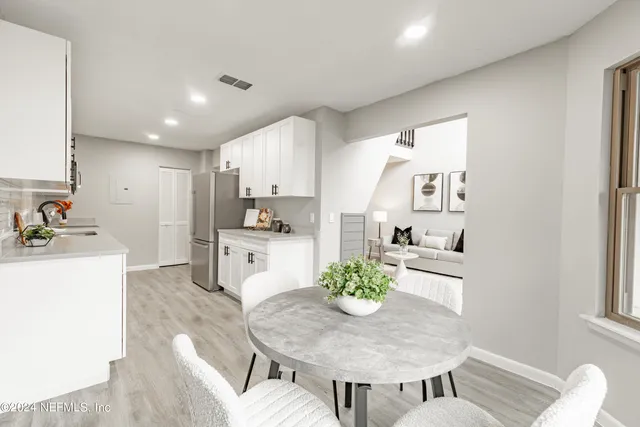 a kitchen with a dining table chairs and refrigerator