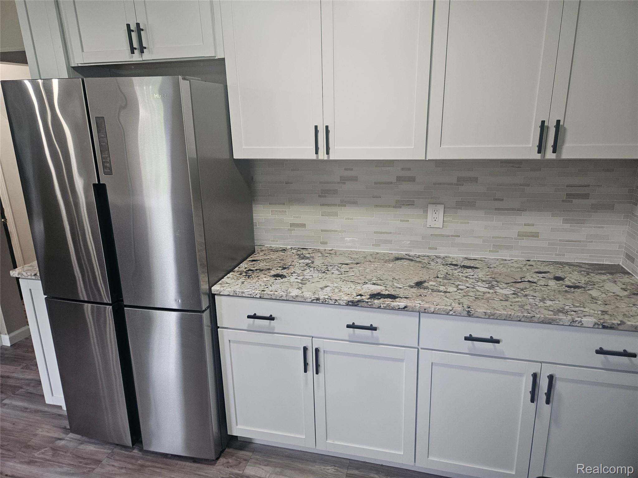 1210 Bay Ridge Drive Highland, MI 48356 - Photo 5 of 25 Kitchen featuring light stone counters, freestanding refrigerator, white cabinetry, and dark wood-type flooring