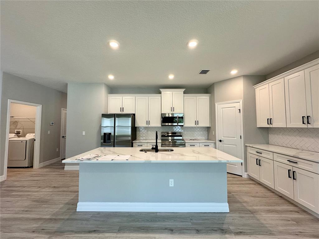 13081 Southwest 78th Circle Ocala, FL 34473 - Photo 4 of 22 a large kitchen with kitchen island a stove a sink a refrigerator and cabinets