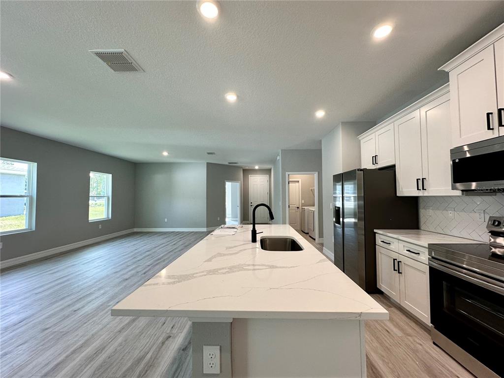 13081 Southwest 78th Circle Ocala, FL 34473 - Photo 6 of 22 a large kitchen with kitchen island a sink stainless steel appliances and cabinets