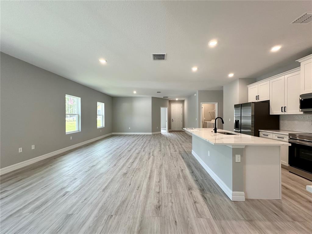 13081 Southwest 78th Circle Ocala, FL 34473 - Photo 7 of 22 a large space with kitchen island a sink dishwasher a stove and a refrigerator with wooden floor