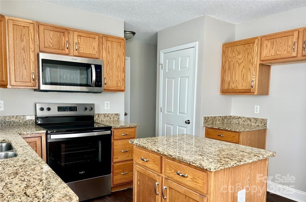 1021 Meadowbrook Lane Southwest Concord, NC 28027 - Photo 6 of 19 a kitchen with granite countertop stove top oven microwave and refrigerator