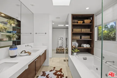 a view of a white house with a big yard potted plants and a bench