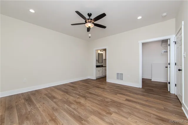 an empty room with wooden floor and a ceiling fan