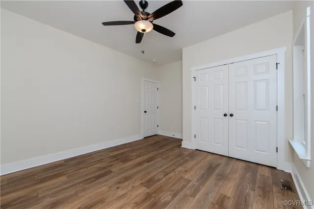 an empty room with wooden floor a ceiling fan and closet