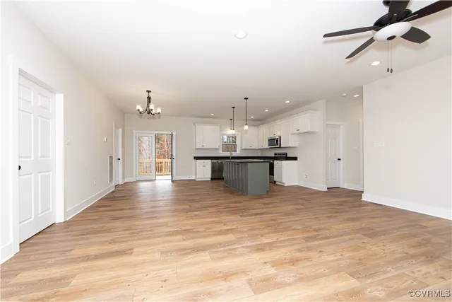 a view of an empty room with kitchen view and a window