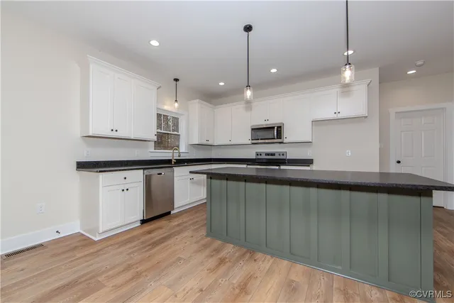 a large kitchen with granite countertop a stove a sink a center island and cabinets