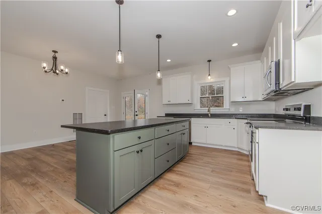 a kitchen with stainless steel appliances granite countertop a sink a stove and a wooden floors
