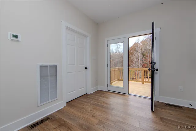 an empty room with wooden floor and windows