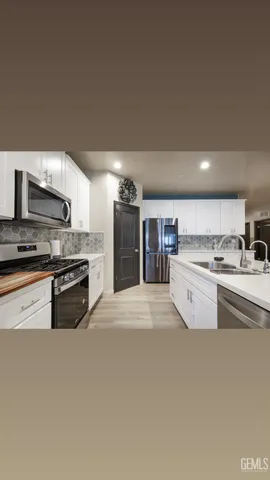 a kitchen with stainless steel appliances kitchen island granite countertop a refrigerator a stove a sink a dining table and chairs with wooden floor