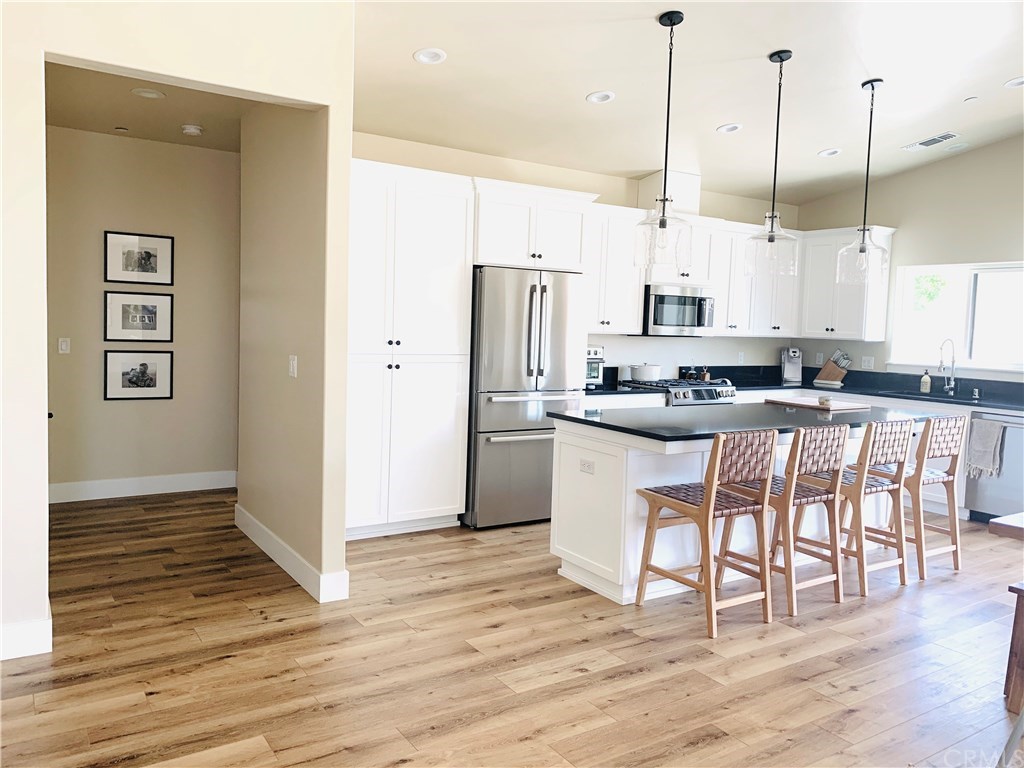 196 Rowan Way Templeton, CA 93465 - Photo 14 of 32 a kitchen with stainless steel appliances kitchen island granite countertop a refrigerator a stove a microwave oven with white cabinets and wooden floor