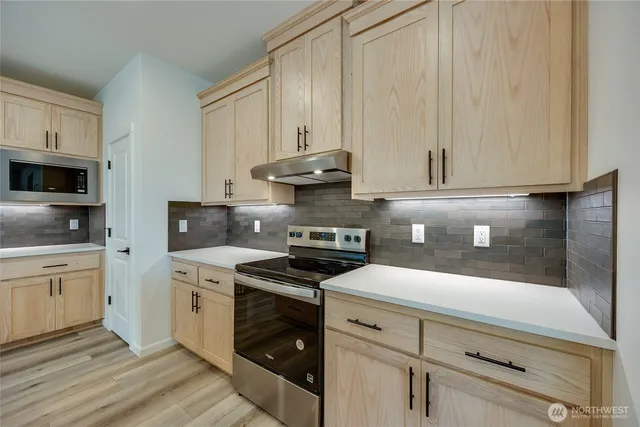a kitchen with stainless steel appliances granite countertop a stove a sink and white cabinets