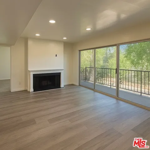 an empty room with wooden floor fireplace and windows